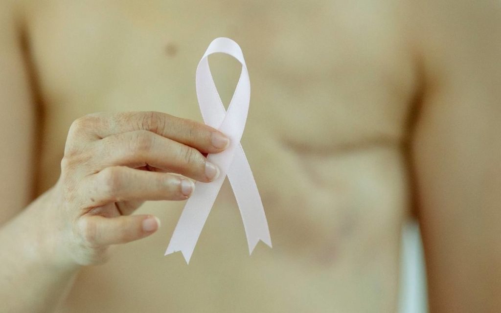 woman that had a lumpectomy holding a pink ribbon